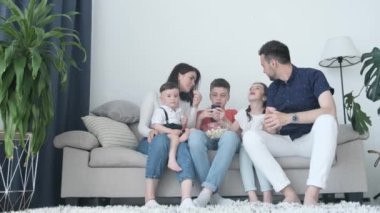 Beş kişilik bir aile - baba, anne, kız ve oğullardan oluşan bir aile akşam televizyon izliyor. Neşeli bir aile evdeki kanepede dinlenip çocuklarla film izliyor..