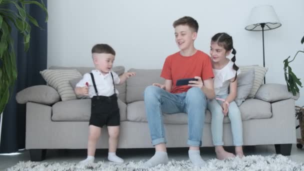 Crianças Estão Brincando Com Smartphone Enquanto Estão Sentadas Sofá Casa — Vídeo de Stock