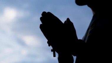 Tespihin üzerinde dua eden bir adamın silueti. Tespihi olan adam. Camilerin imamı. Din kavramı