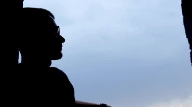 Mavi gökyüzünün arka planında bir adamın silueti, yüksek sesle konuşur ya da şarkı söyler. 4k video