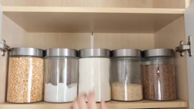 Mısır gevreği depolamak için konteynırlar. Bir kadının eli bir kavanoz mısır gevreği alır. Gevşek ürünler. Sağlıklı organik gıda