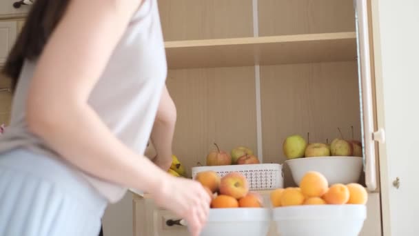 머리를 여자는 창고에 과일을 넣는다 부엌에 브루넷 여성입니다 — 비디오