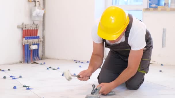 若い男性の建築家が床にセラミックタイルを敷いています 新しい建物で修理する 4Kビデオ — ストック動画