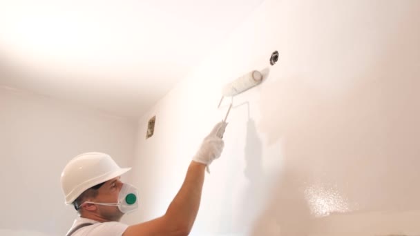 一个年轻人当画家 在新的建筑或公寓楼里用滚子在室内画墙壁 — 图库视频影像