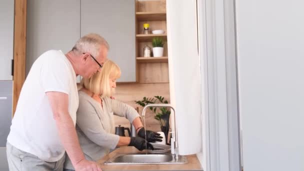 ラテックス手袋料理で引退した女性は 彼女の愛する夫は彼女を助ける 祖父と祖母が一緒に皿を洗う 4Kビデオ — ストック動画