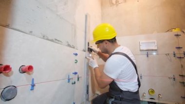Seramik fayansların kurulumunun kontrolü. Sarı kasklı bir mühendis inşaat çalışmalarının doğruluğunu kontrol ediyor..