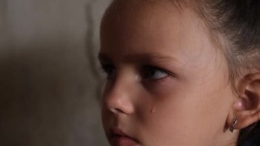 Yüzünde yaşlarla küçük bitkin bir kız bomba sığınağında oturuyor. Bodrumlarda bombardıman sırasında çocuklar. Rusya 'nın Ukrayna' ya karşı savaşı