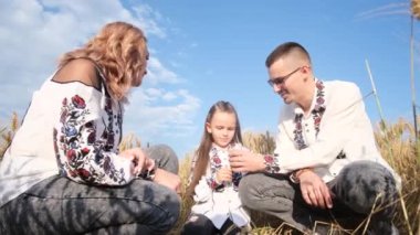 Kızlarıyla buğday tarlasında güzel bir çift. Genç bir aile Vyshyvanka 'nın Ukrayna ulusal kıyafetlerini giyiyor..