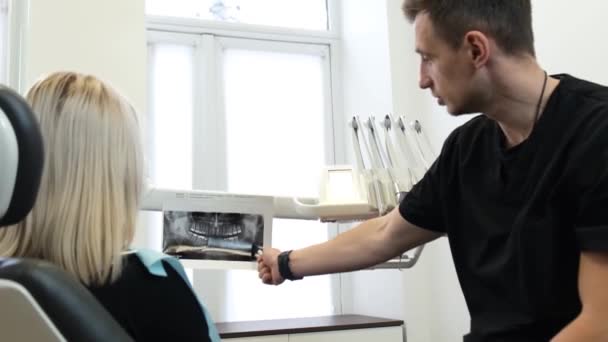 一名专业牙医向来访的女性展示了一副X光牙齿 在看医生的过程中 在牙科诊所里的一位积极的女病人 牙科治疗概念 — 图库视频影像
