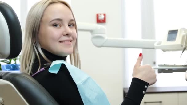 歯科医の椅子に座って笑って幸せな笑顔のブロンドの女性 歯のホワイトニング後の患者を満足させます 近代歯科学 — ストック動画