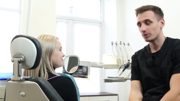 一位坐在牙医椅子上的妇女在治疗过程中看着她的牙齿 病人对牙科治疗很满意 与牙医的沟通 — 图库视频影像