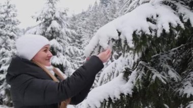 Karlı bir Noel ormanında beyaz şapkalı bir kız. Mutlu kız dışarıda eğleniyor. Noel zamanı. 