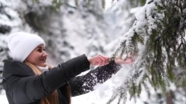 Tatlı kız kış ormanlarında kar tanelerinin altında dururken mutlu bir şekilde Noel ağacını sallıyor. Bir kız ilk karın tadını çıkarır.