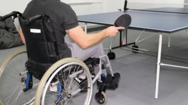 Tekerlekli sandalyedeki bir çocuk masa tenisi oynuyor. Engelli sporları. 4k video