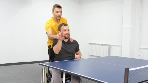 身体障害のある男が車椅子に座り 卓球をしている トレーナーは障害者を訓練する 競技者の再生 — ストック動画