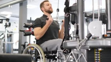 Tekerlekli sandalyedeki bir adam spor salonunda çalışıyor. Spor gelişimi kavramı.