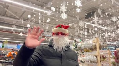 Noel Baba maskeli bir adam kameraya bakarken elini sallıyor. Yeni Yıl ve Noel 2023 konsepti