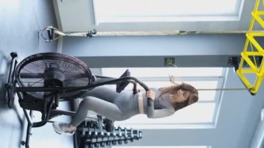 Spor salonunda egzersiz bisikletini kardiyo için kullanan genç bir kız. Dikey video. Yavaş çekim