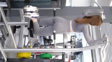 Sportif kız spor salonunda barfiks çekiyor. Profesyonel bir atlet güç egzersizleri yapar. Dikey video
