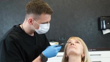 Profesyonel bir estetik cerrah yaşlı bir kadını muayene eder ve estetik ameliyattan önce yüz izi bırakır. Modern Avrupa Estetik Cerrahi Kliniği