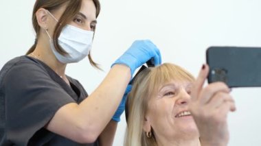 Yaşlı ve güzel bir kadın bir trikoloğla randevuda. Yaşlılıkta saç bakımı ve tedavi. Modern Avrupa Kliniği