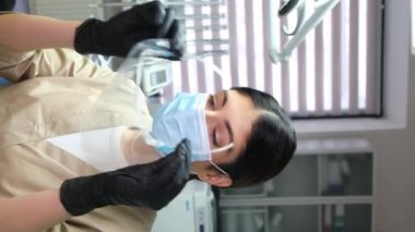 Kadın doktor koruyucu bir maske takıyor, dikey video. Koronavirüse karşı koruma. Profesyonel doktor.