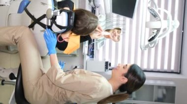 Dikey video, kadın dişçi muayene eder ve hastaların dişleri üzerinde çalışır. Ağız sağlığı konsepti. 4k video