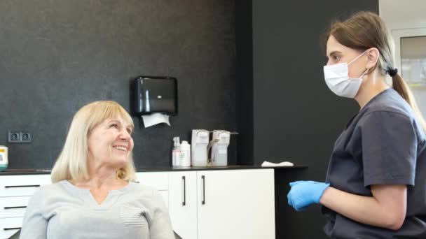 祖母は椅子に座りながら歯医者と話している 古い歯の状態を確認してください 医者は患者に相談する 近代歯科学 — ストック動画