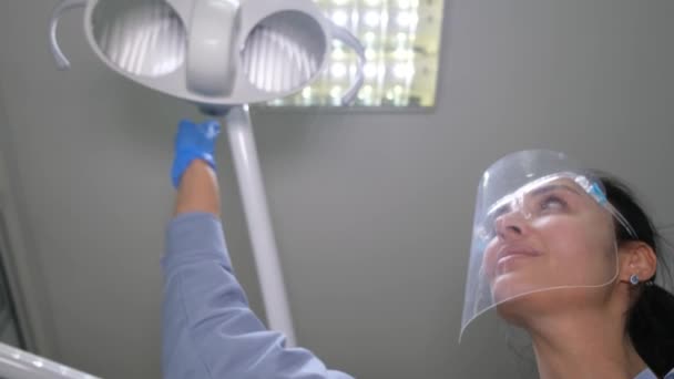 Улыбающаяся Стоматолог Осматривает Пациента Освещая Лицо Профессиональной Лампой Лечение Зубов — стоковое видео