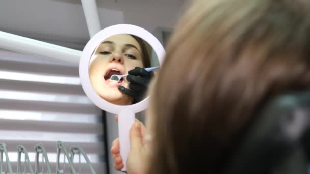 歯医者の手の魅力的な女性の歯の作業を閉じます 患者は鏡を見て彼女の笑顔を賞賛する — ストック動画