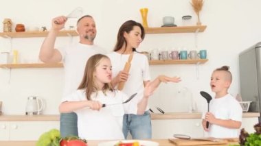 Mutfakta iki çocukla dans eden bir aile. Aile görünüşü. Mutlu aile hafta sonu