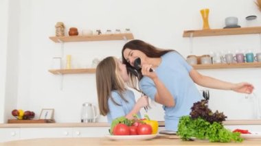 Anne ve kız sevgisi. Mutlu bir aile eğleniyor, modern bir mutfakta dans ediyor ve sağlıklı yemekler pişiriyor. Mutlu aile günleri..