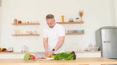 Çekici, orta yaşlı bir adam modern bir mutfakta karısı için yemek hazırlıyor. Evde birbirine aşık bir çift. Sağlıklı aile yemeği.