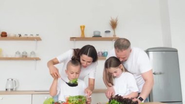 İki çocuklu mutlu ve arkadaş canlısı bir aile mutfakta birlikte sağlıklı bir öğle yemeği hazırlıyor. Ailecek vakit geçireceğiz. Vejetaryen ailesi