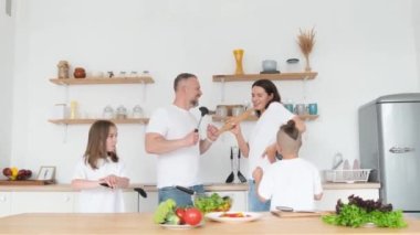 Mutfakta modern bir iç mekanla dans eden iki çocuklu çılgın mutlu bir aile. Dans eden aile. Keyfin yerinde.