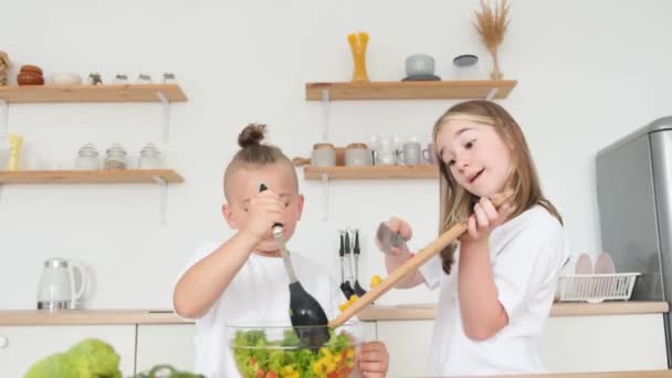 モダンなキッチンで新鮮な野菜サラダを準備するかわいい男の子と女の子 家にいる子供たち 健康的な食事 — ストック動画