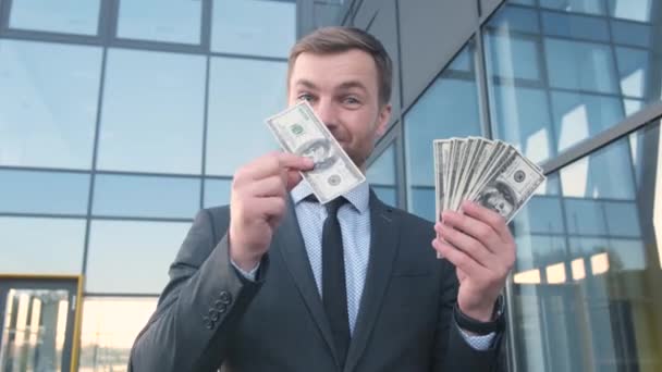 非常に幸せな豊かな若い男 ビジネスマン ドルの山の監督 現代の超高層ビルを背景にハンサムな髭のビジネスマン — ストック動画