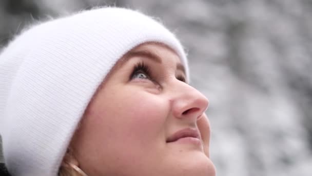 一个戴着白帽的迷人的年轻女子的特写 面对着树木和雪堆的背景 优质4K视频 — 图库视频影像