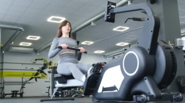 Seksi bir kadın spor salonunda modern bir simülatörde spor yapıyor. Fitness yaşam tarzı konsepti.