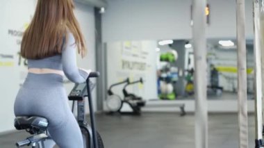 Spor salonunda uzun saçlı güzel bir kadının egzersiz egzersizi, egzersiz bisikleti. Sağlıklı vücut kavramı