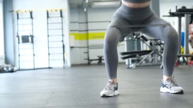 Videoda, bir kadın modern bir spor salonunda bacak kaslarını çalıştırıyor. Kapsamlı fitness eğitimi. Sağlıklı vücut kavramı.