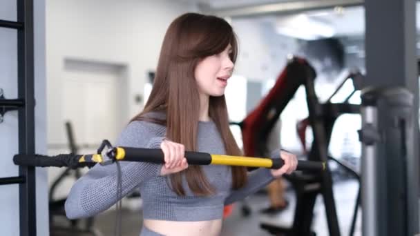 迷人的欧洲年轻女运动员在体育馆里锻炼胳膊肌肉 现代模拟器的力量训练 — 图库视频影像