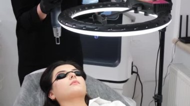 Genç bir kadın güzellik salonunda kalıcı makyaj malzemelerinin lazerle çıkartılmasına maruz kalıyor. Kaş düzeltmesi, yakın plan. 4k video