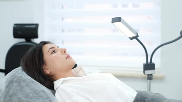 椅子に寝そべっている美容師の医者を待っている若い美女 現代美容クリニック — ストック動画