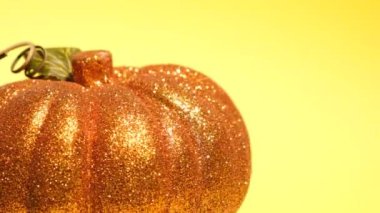 Altın balkabağı şeklinde bir Noel oyuncağıyla parlak sarı arka plan. Yeni yıl kavramı