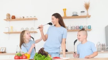 Mutlu anne kız ve oğul eğleniyor, mutfakta müzik eşliğinde dans ediyorlar. Aile görünüşü. Birlikte mutluyuz.