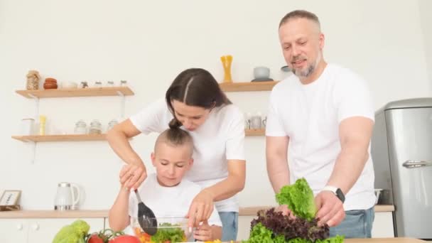 아버지 어머니 아들은 야채를 사용하여 건강에 샐러드 준비하고 현대의 부엌에 — 비디오