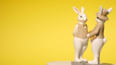 Yakın plan, sarı arka planda Paskalya tavşanı şeklinde seramik oyuncak. Mesaj için yer. 4k video