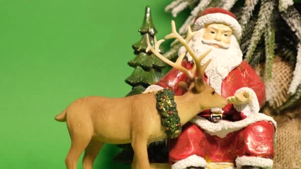 サンタクロースの形をした美しい陶器のおもちゃと緑の背景に鹿 4Kビデオ — ストック動画
