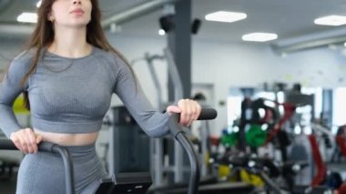 Spor salonunda uzun saçlı güzel bir kadının egzersiz egzersizi, egzersiz bisikleti. Sağlıklı vücut kavramı